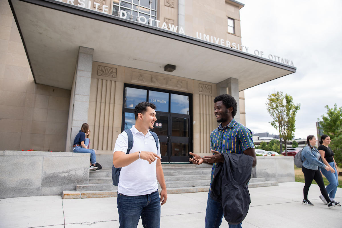 Two students talking outside campus building. 