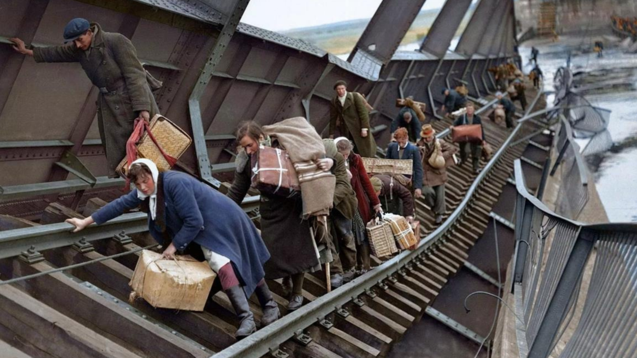 A group of people are climbing over a damaged bridge.
