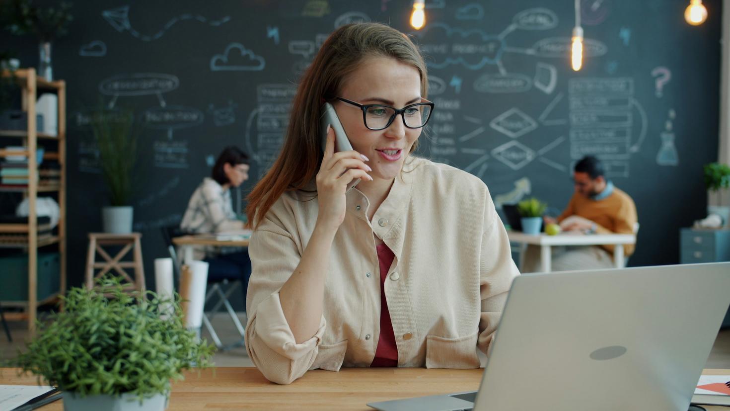 Young woman professional on the phone in front of computer