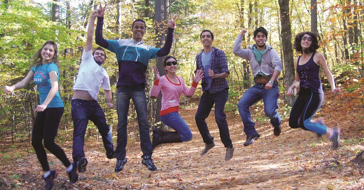 International Students jumping together in the forest