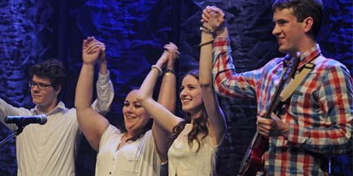 Students celebrating by holding hands and raising their arms.