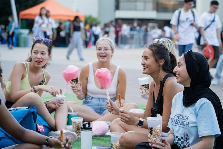 A group of friends laughing and sitting on the grass outdoors.