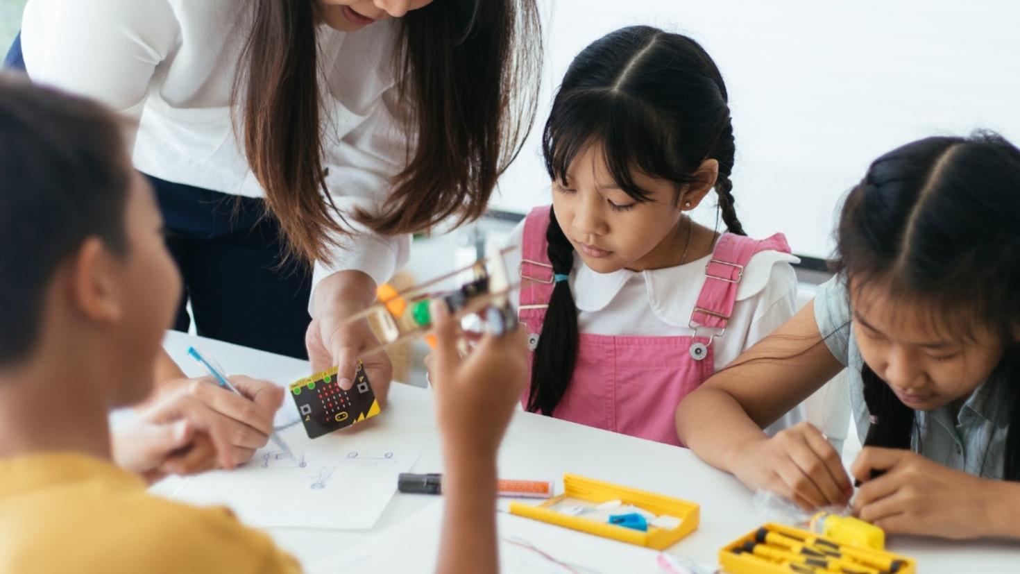 Teacher helping young students with technology
