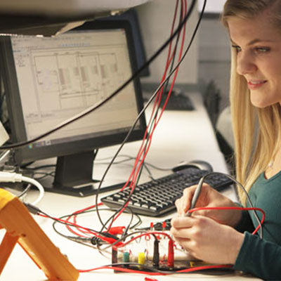 Student working with wires and computer equipment.