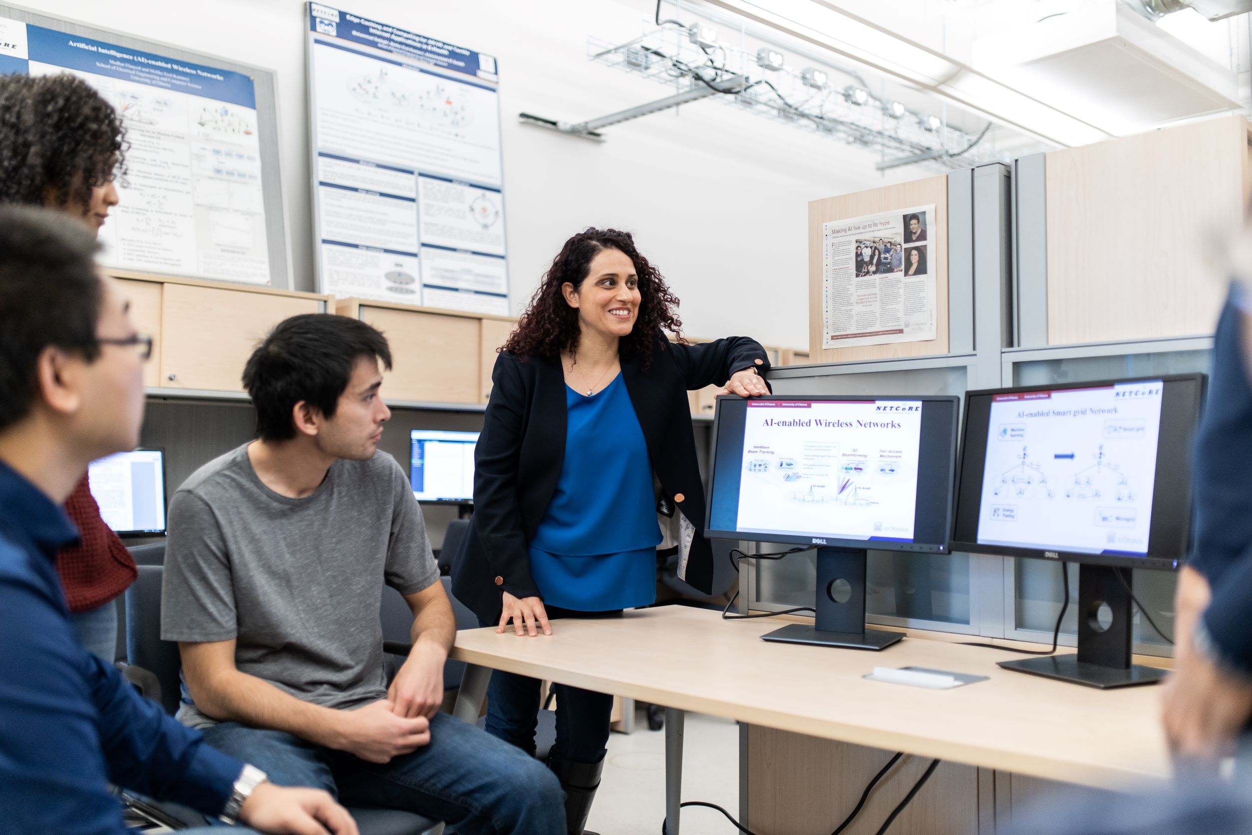 A group of student and a professor assembled around computer screens.