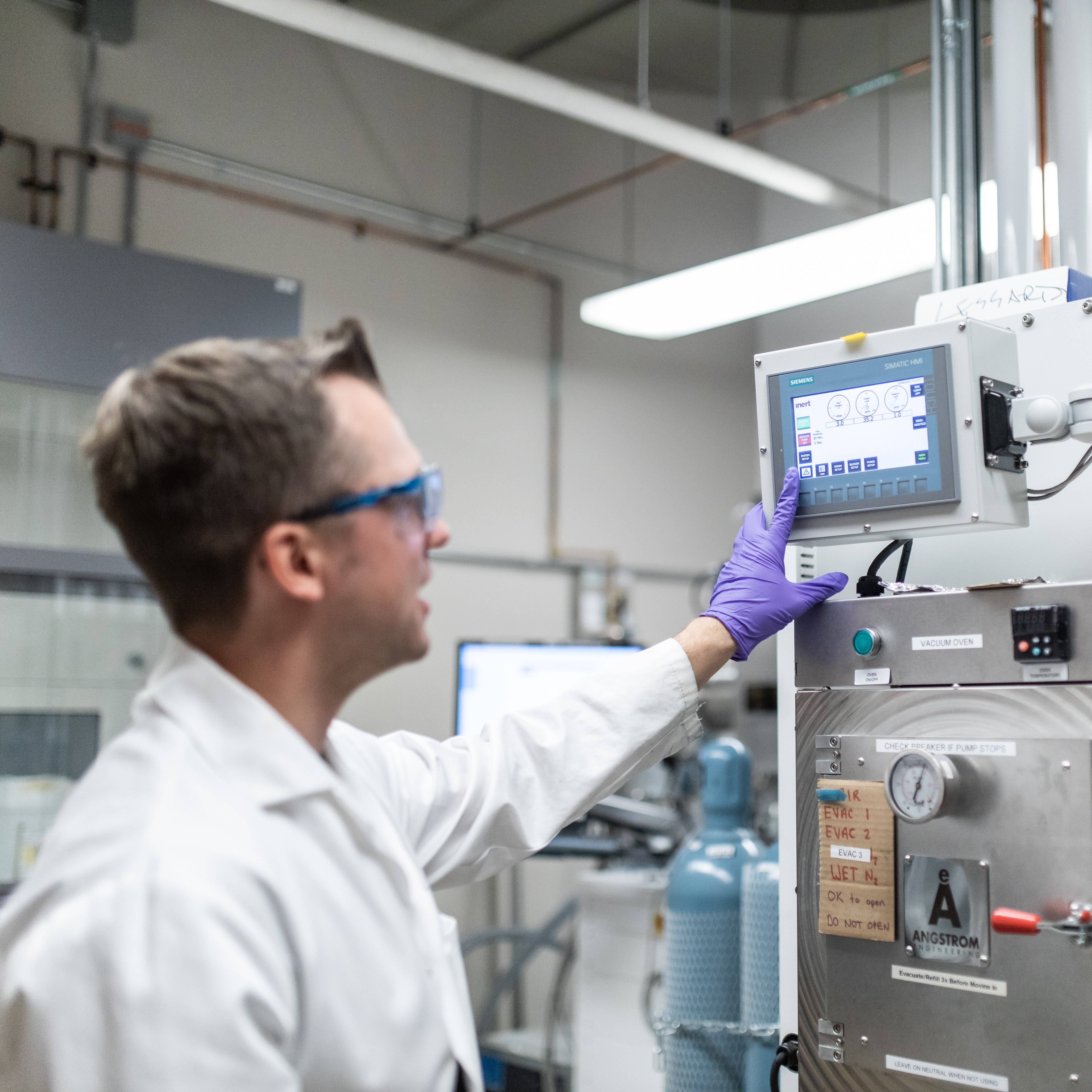 A researcher looks at a monitor on a machine in a lab.