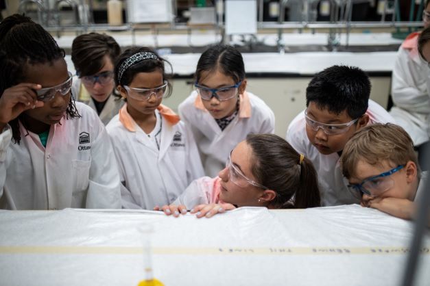 Instructor surrounded by children during an experiment.