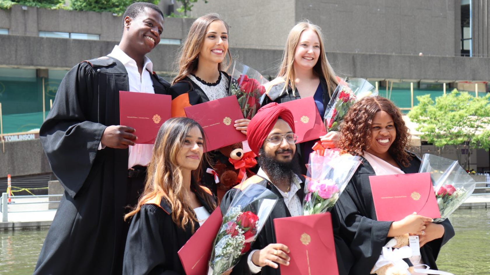 Group of people holding their diplomas in their cap and gowns.