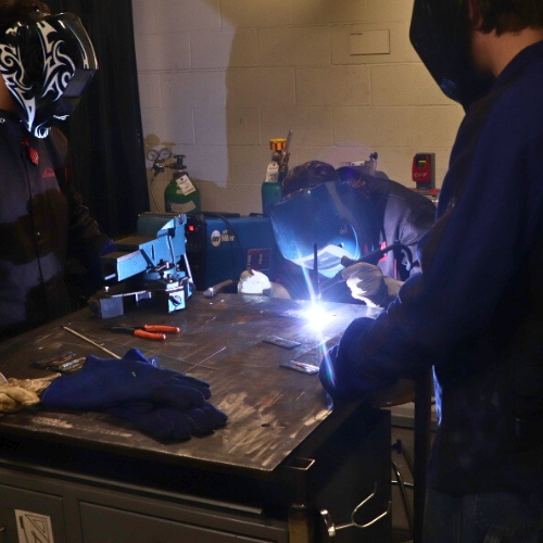People gathering around welding station. One person is welding.