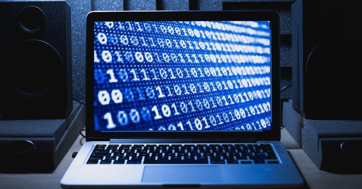 A laptop screen open with a series of ones and zeros.