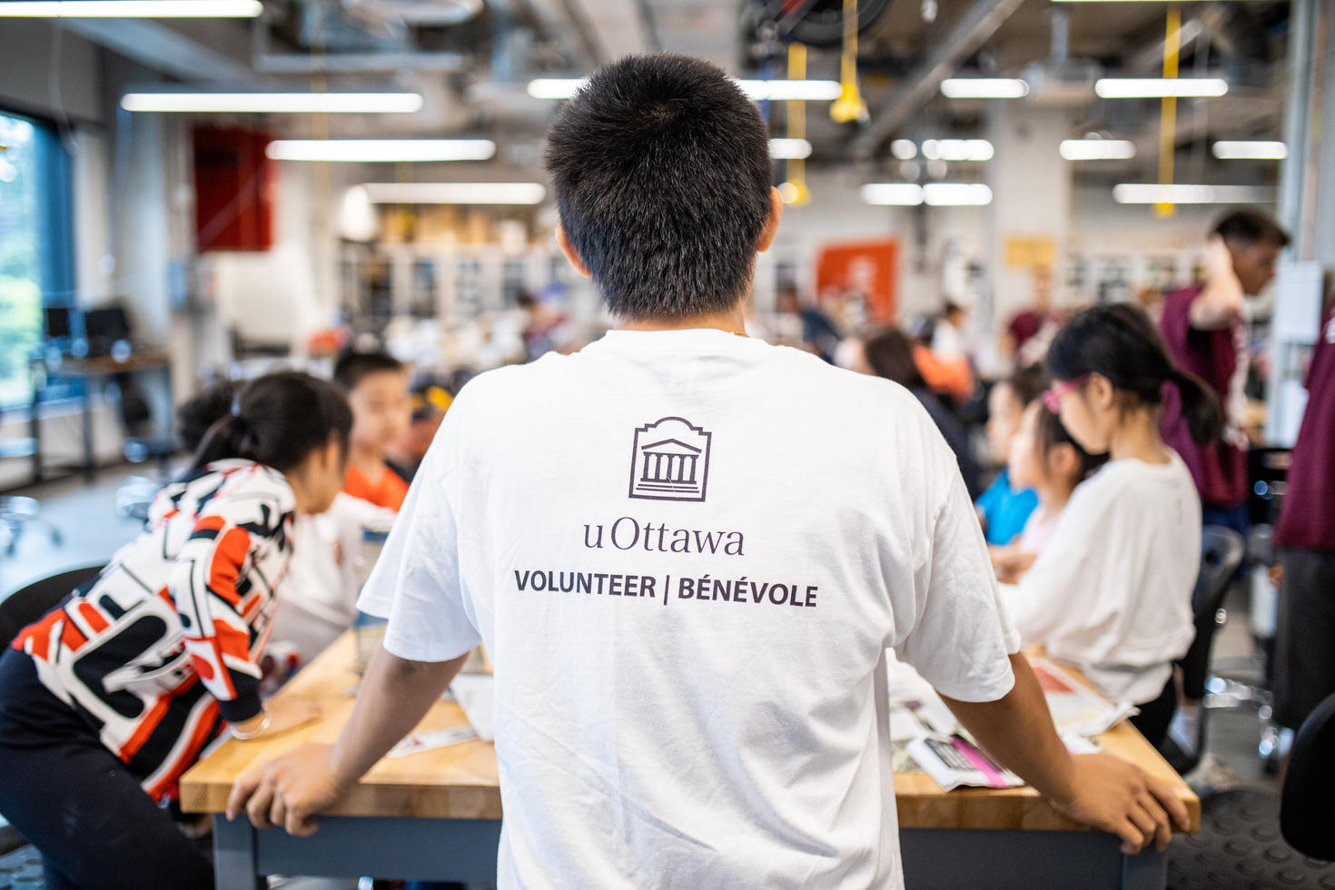 Back of a teenager standing in front of group wearing uOttawa volunteer t-shirt.