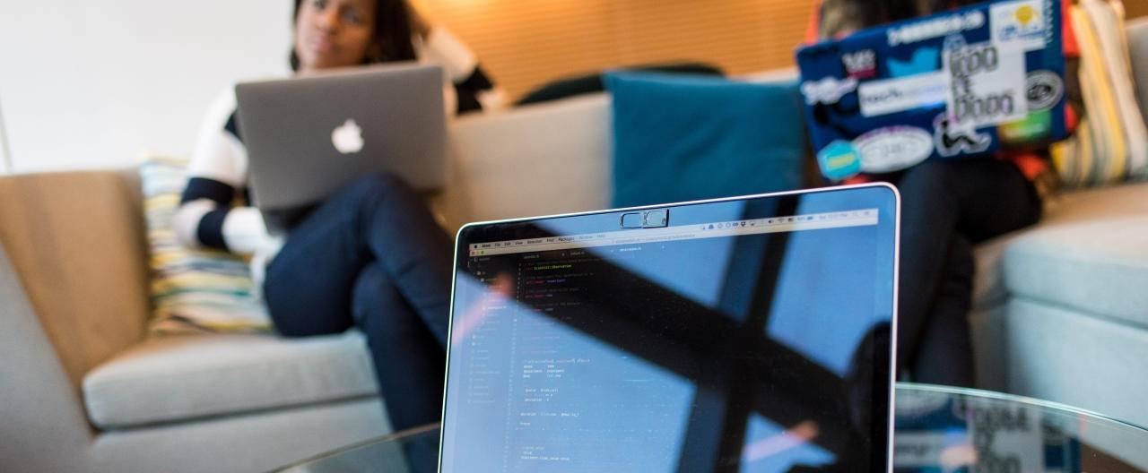 Students on their computers. There is code visible on the screen.