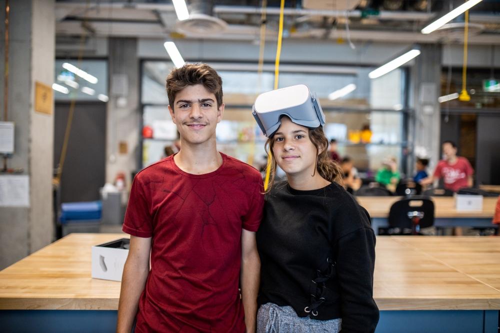 Two teenagers in an engineering workspace.