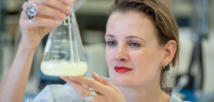 Elena Baranova looking at a glass beaker.
