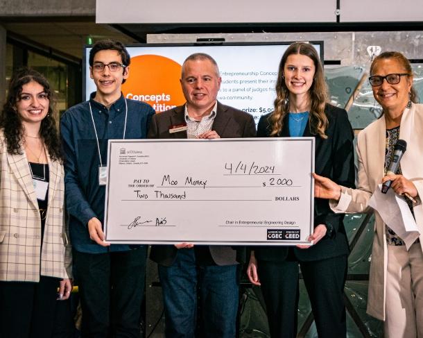 Winning students standing on the stage with a large check.