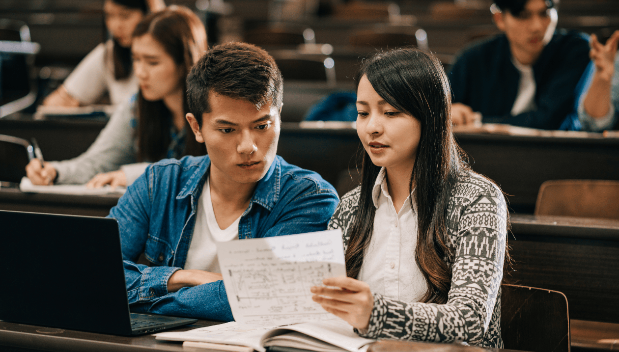 Two students looking at papers in classroom.