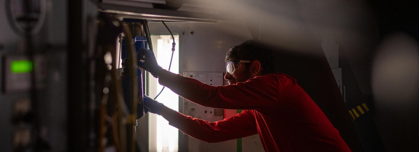 A graduate student arranging settings in a mechanical engineering experiment.