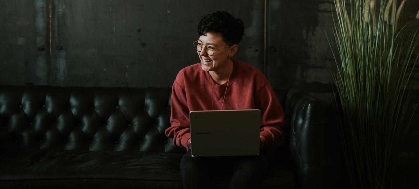 student smiling to the side with a laptop on her lap