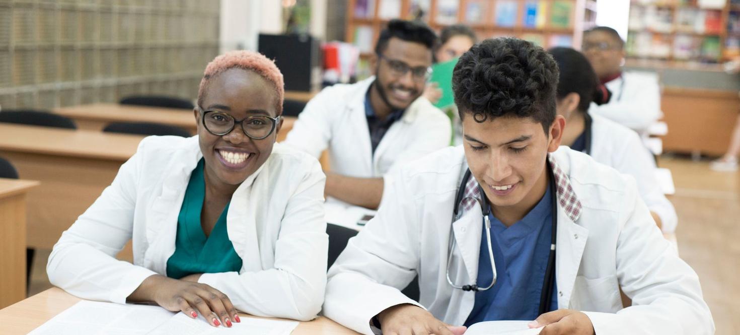 A group of nursing students sit at desks in a classroom