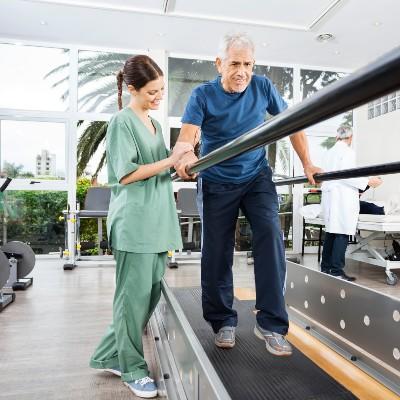 A woman helps a man walk with guardrails