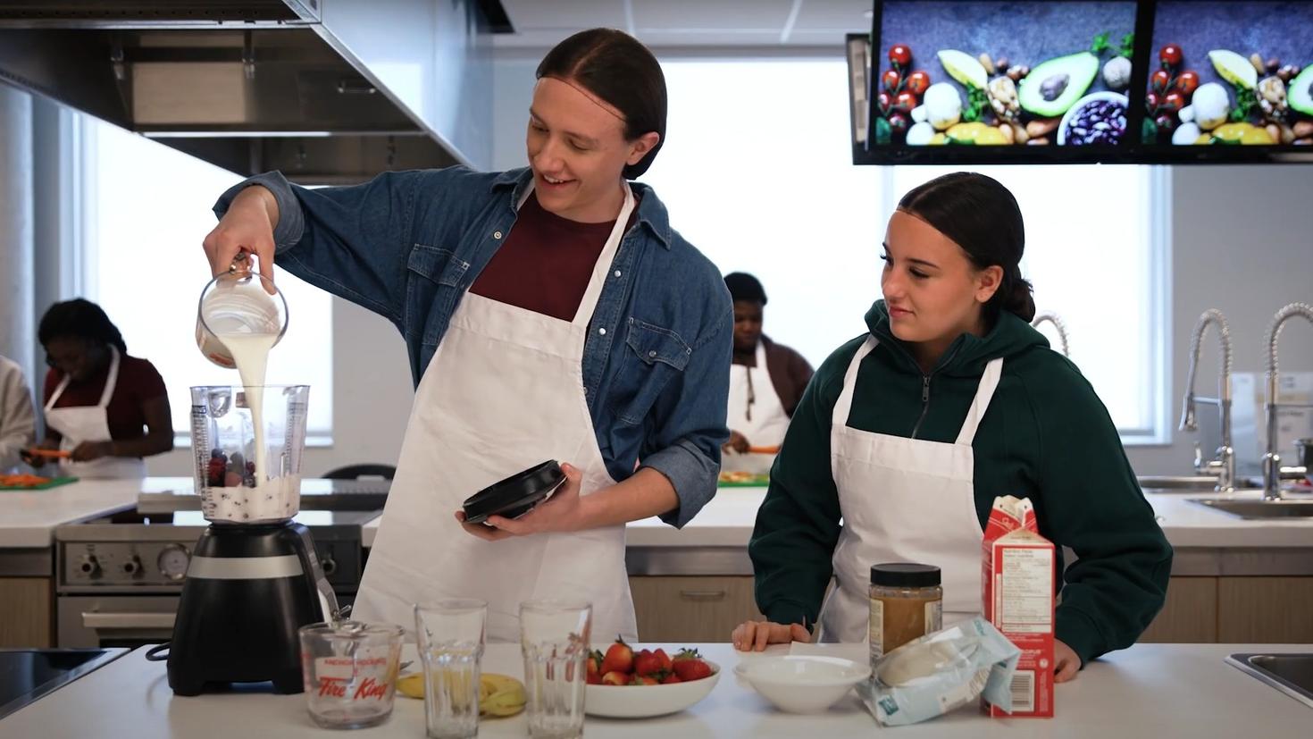 2 students cooking together in a commercial kitchen