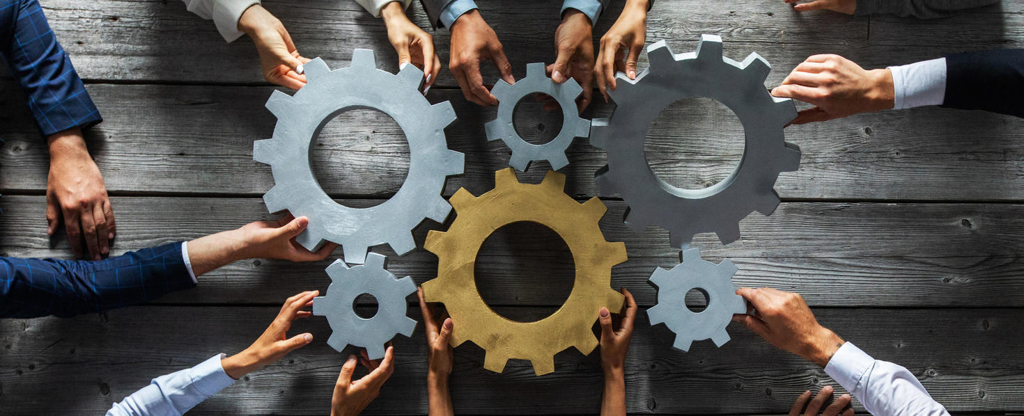 A group of people working together to align gears on a wooden table