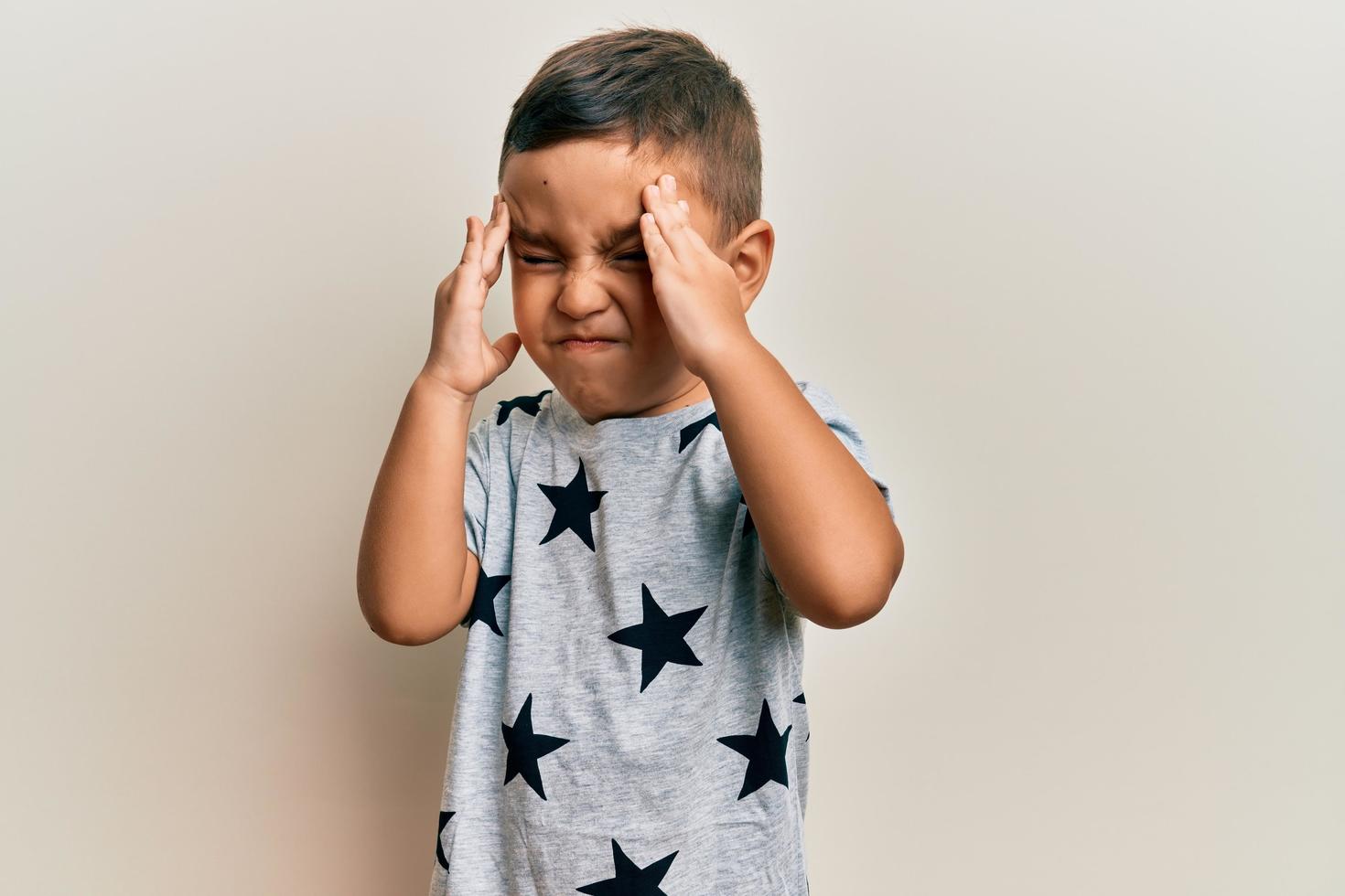 A young child holds his head in pain