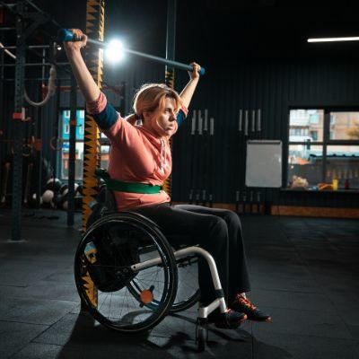 woman in wheelchair liftin weights above her head