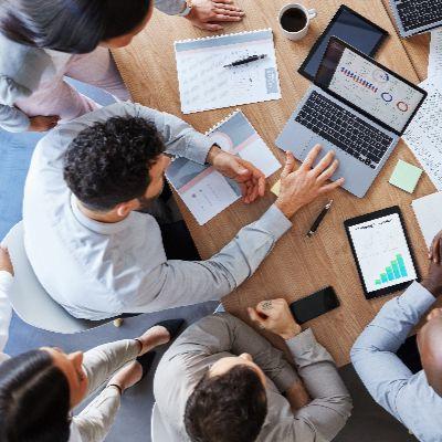 A group of students do research on a table, shot from above.