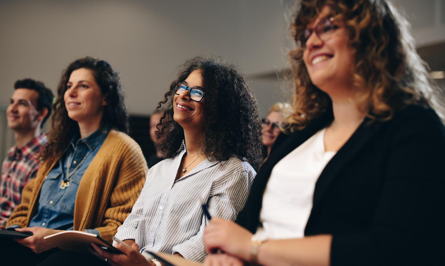 Photo of women smiling, listening to a conference
