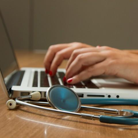 Medical professional typing on a laptop