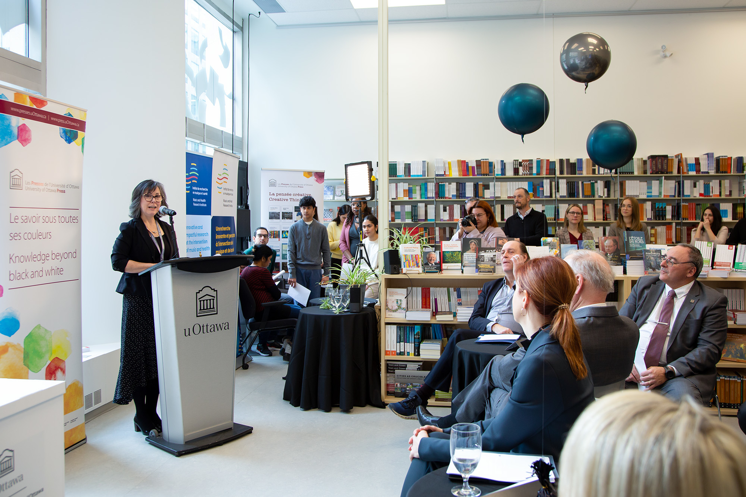 A woman standing at a podium during the opening ceremony of the uOttawa Press