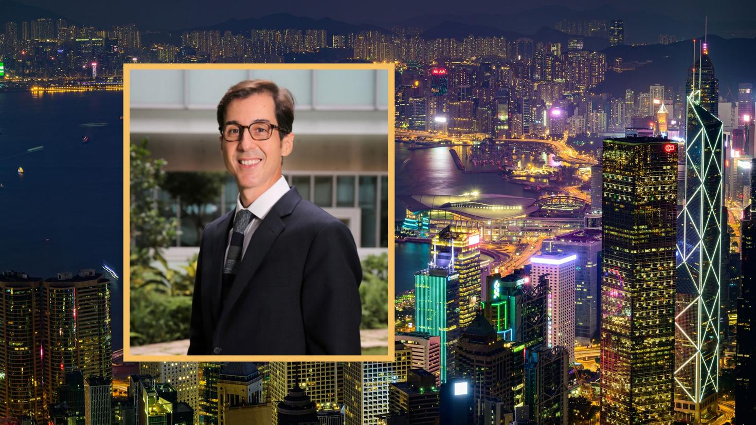 A picture of Marcelo Thompson behind a skyline view of Hong Kong at night. 