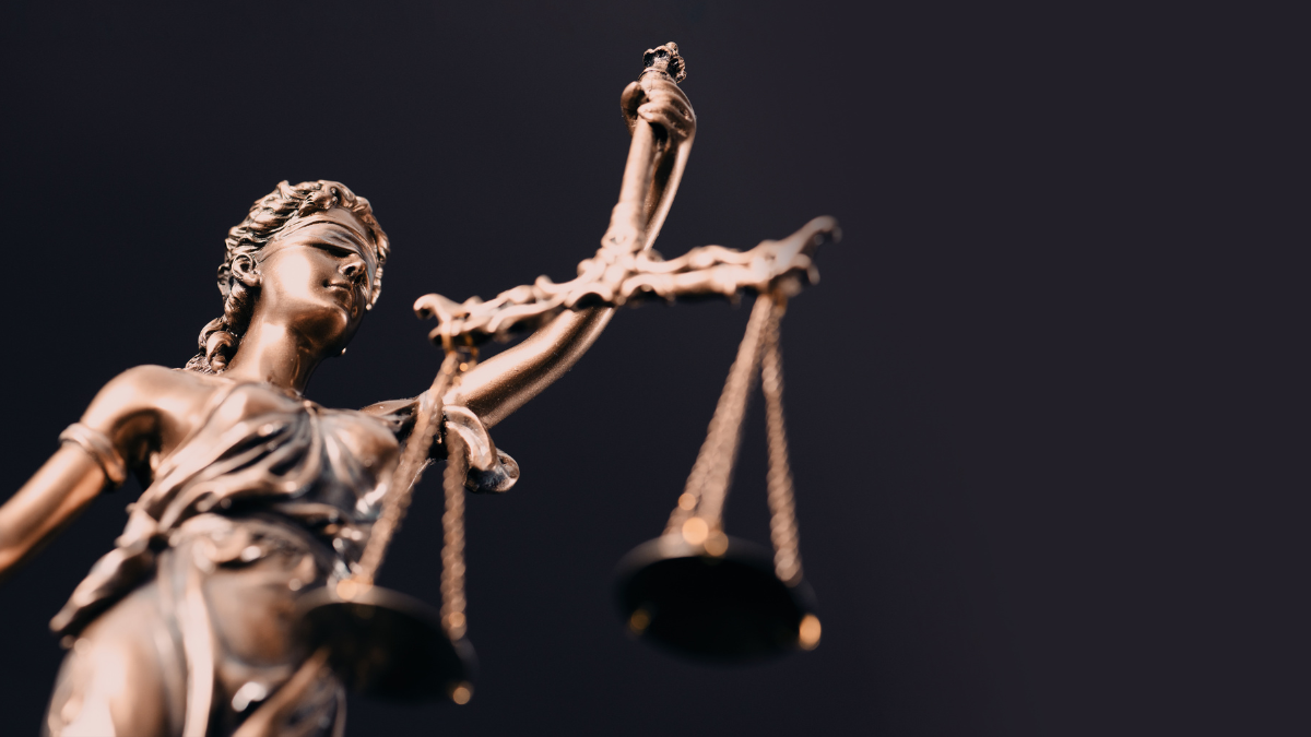 Statue of Lady Justice with blindfold and holding up scales, against a black background.