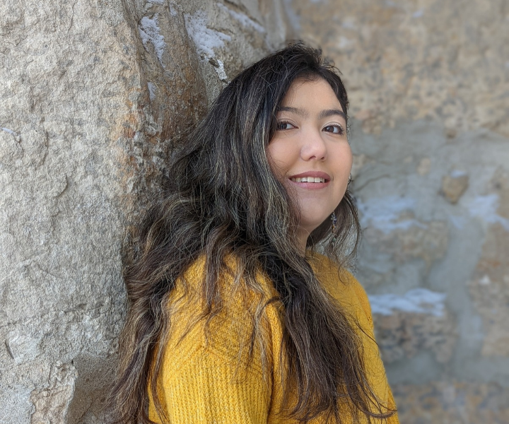 Young woman posed in front of a rock wall