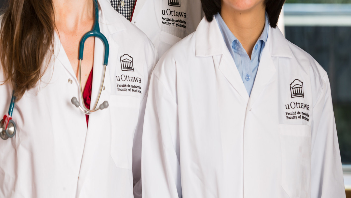 Three individuals wearing Faculty of Medicine lab coats.