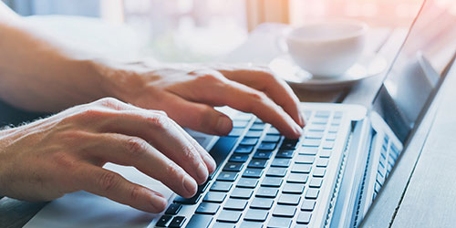 Two hands typing on a laptop keyboard