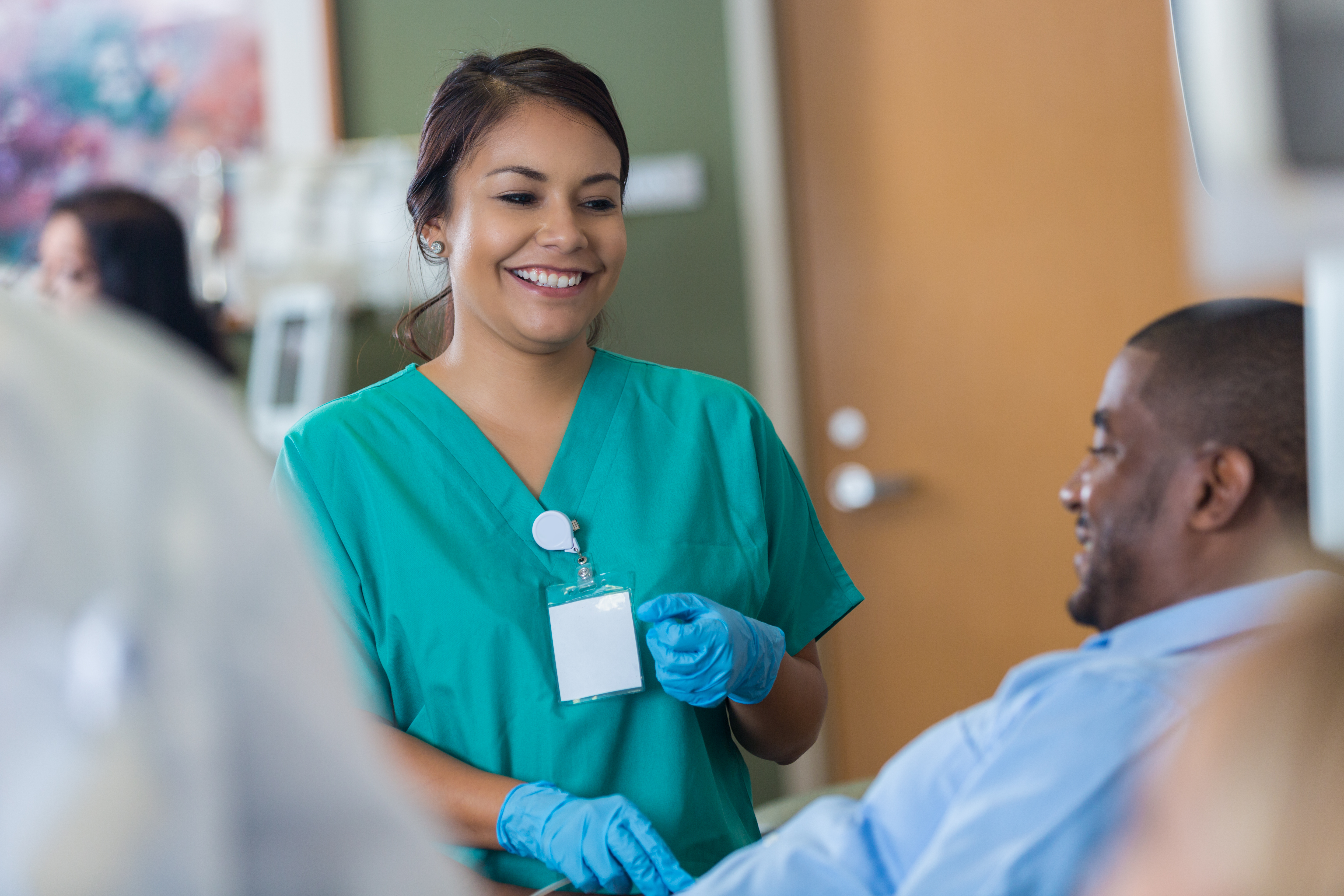 Cheerful young Hispanic female nurse checks vital signs on African American male blood donor.