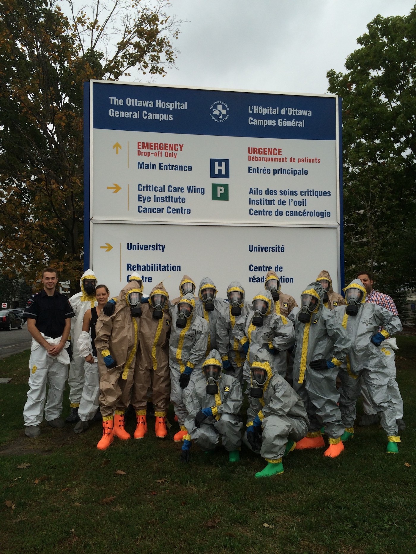 Group of paramedics in hazmat suits in front of Hospital sign