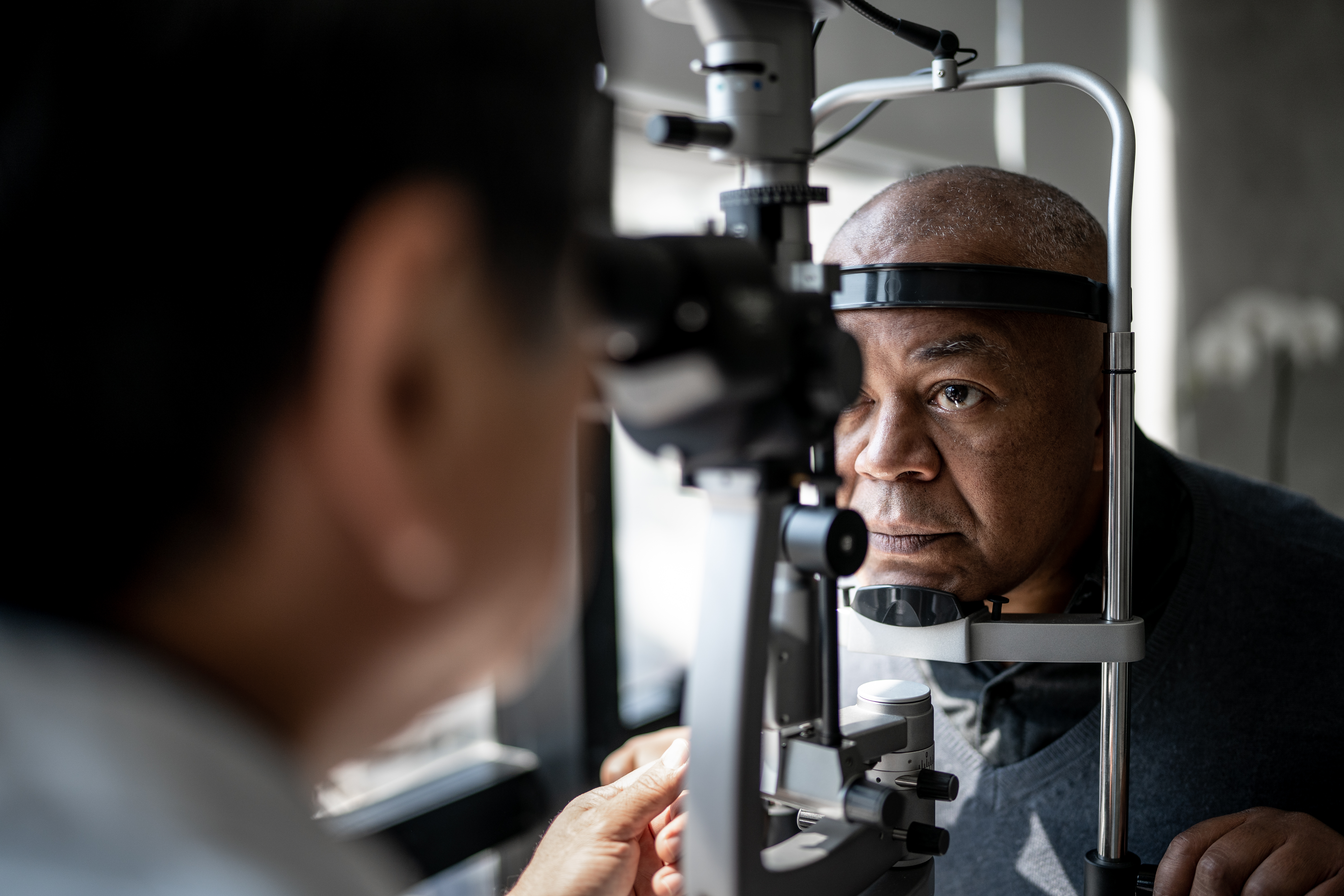 Physician examining a male African-American patient at slit lamp