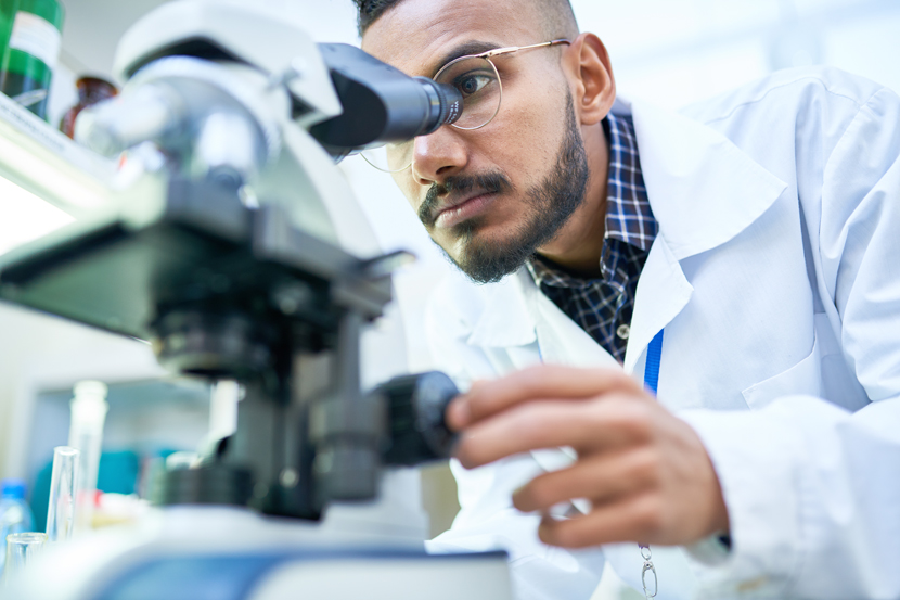 a researcher looking in a microscope