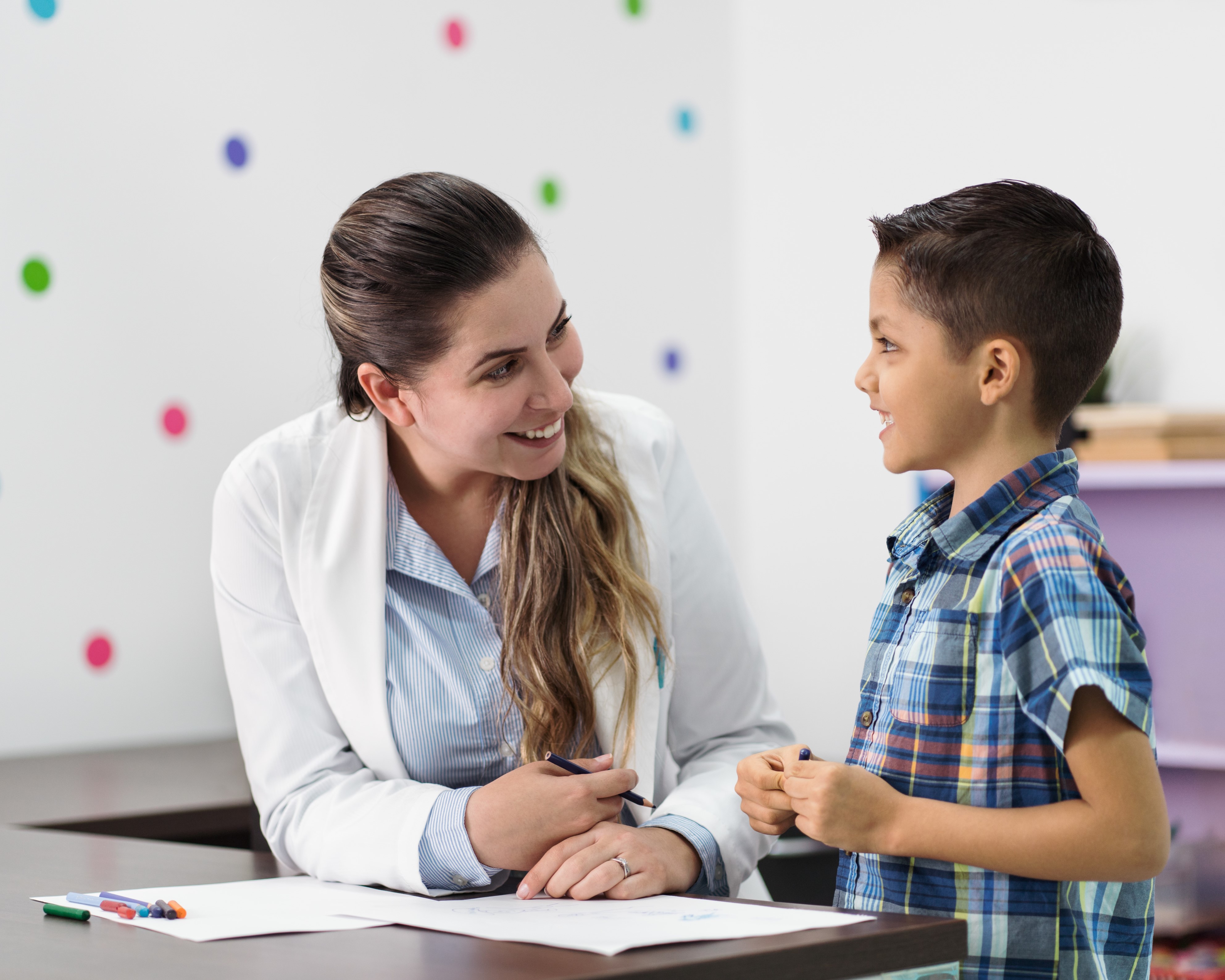 Happy psychologist and little boy smiling at each other