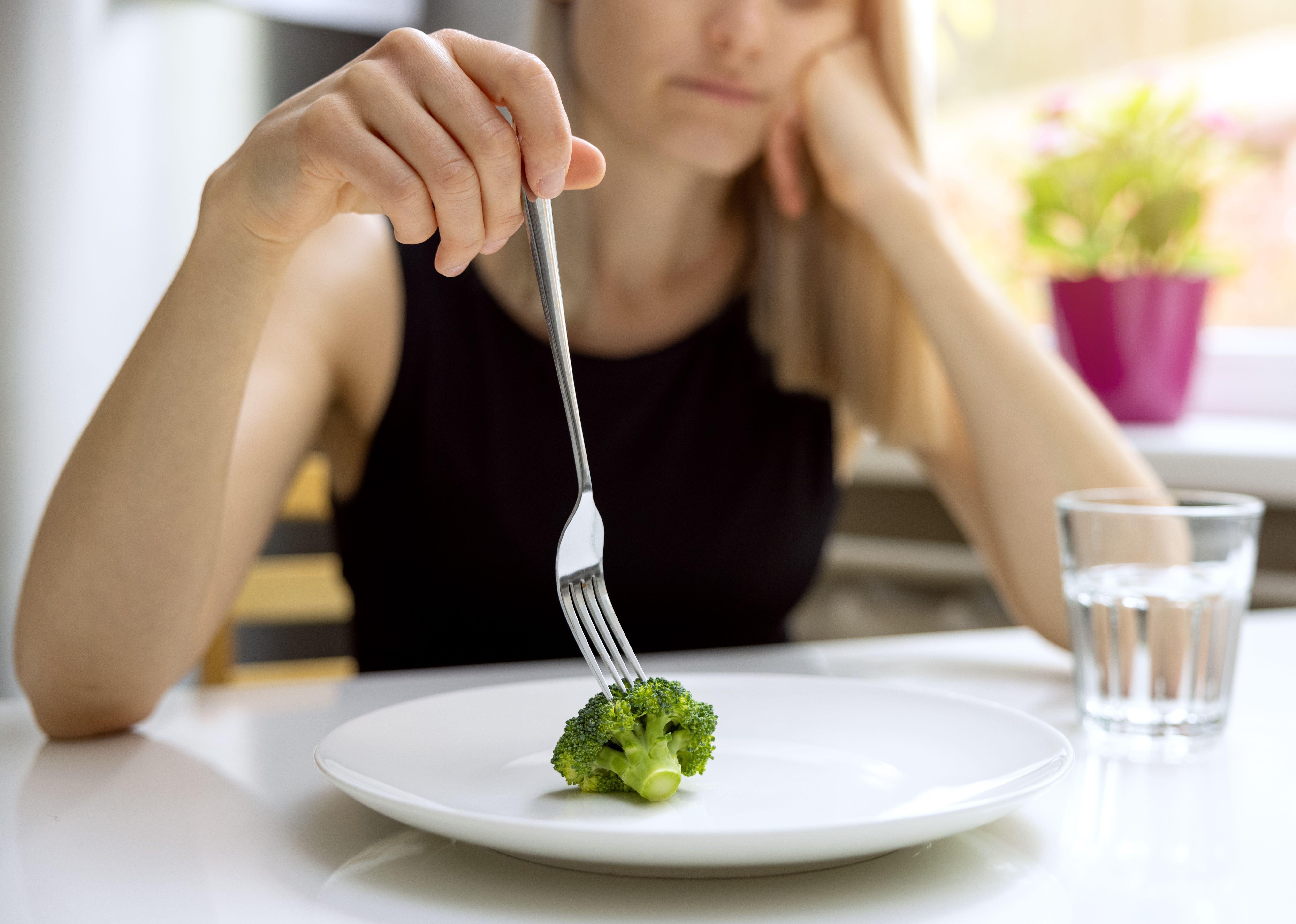 Unhappy woman looking at a small broccoli portion on the plate