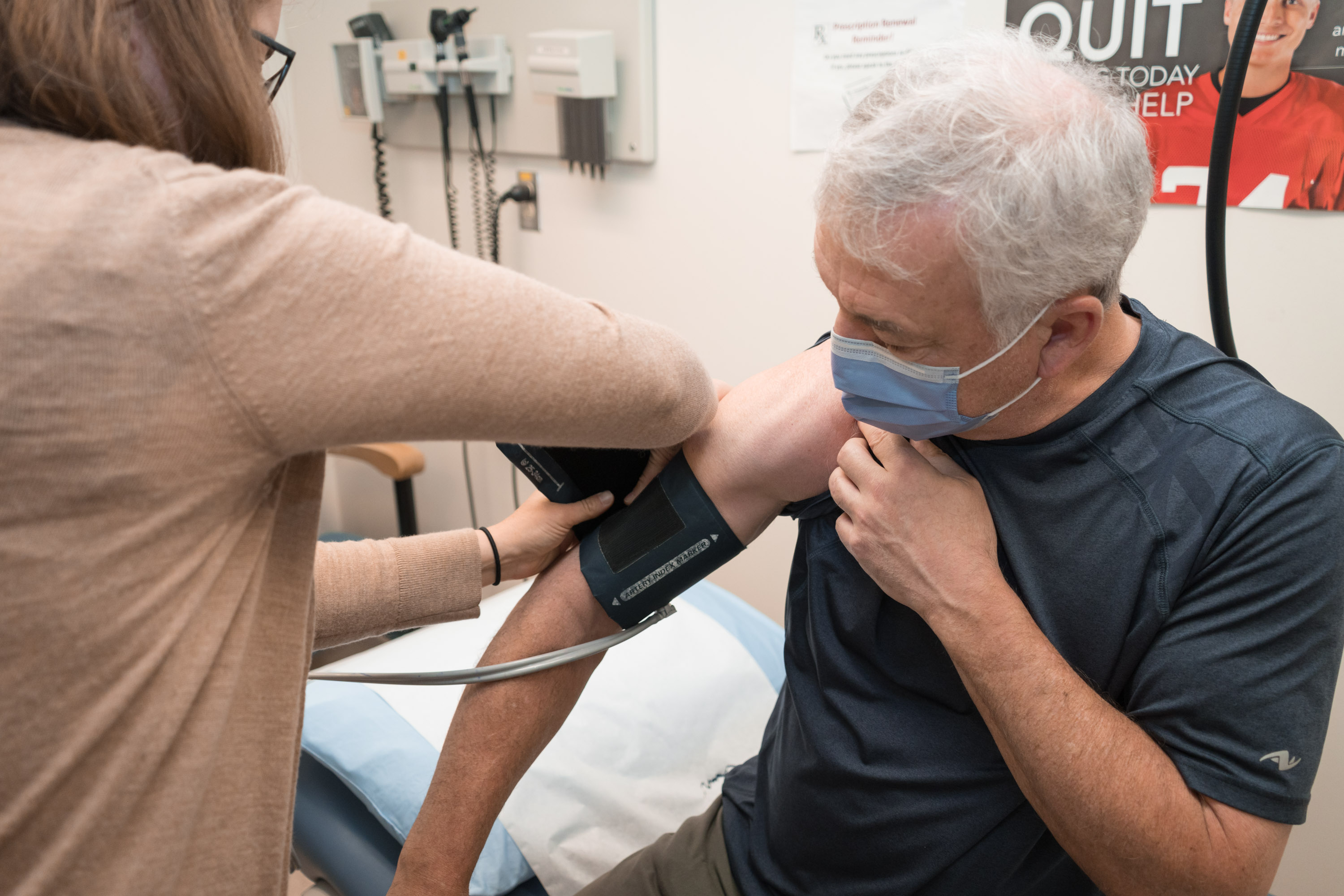 doctor putting blood pressure monitor on male patient