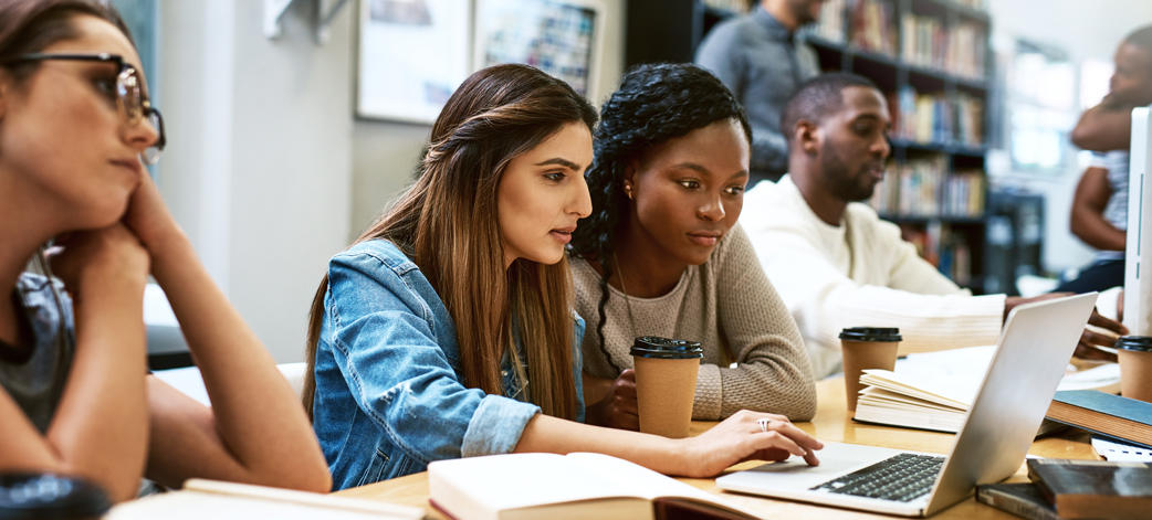 Shot of two young women using a laptop together in a college library