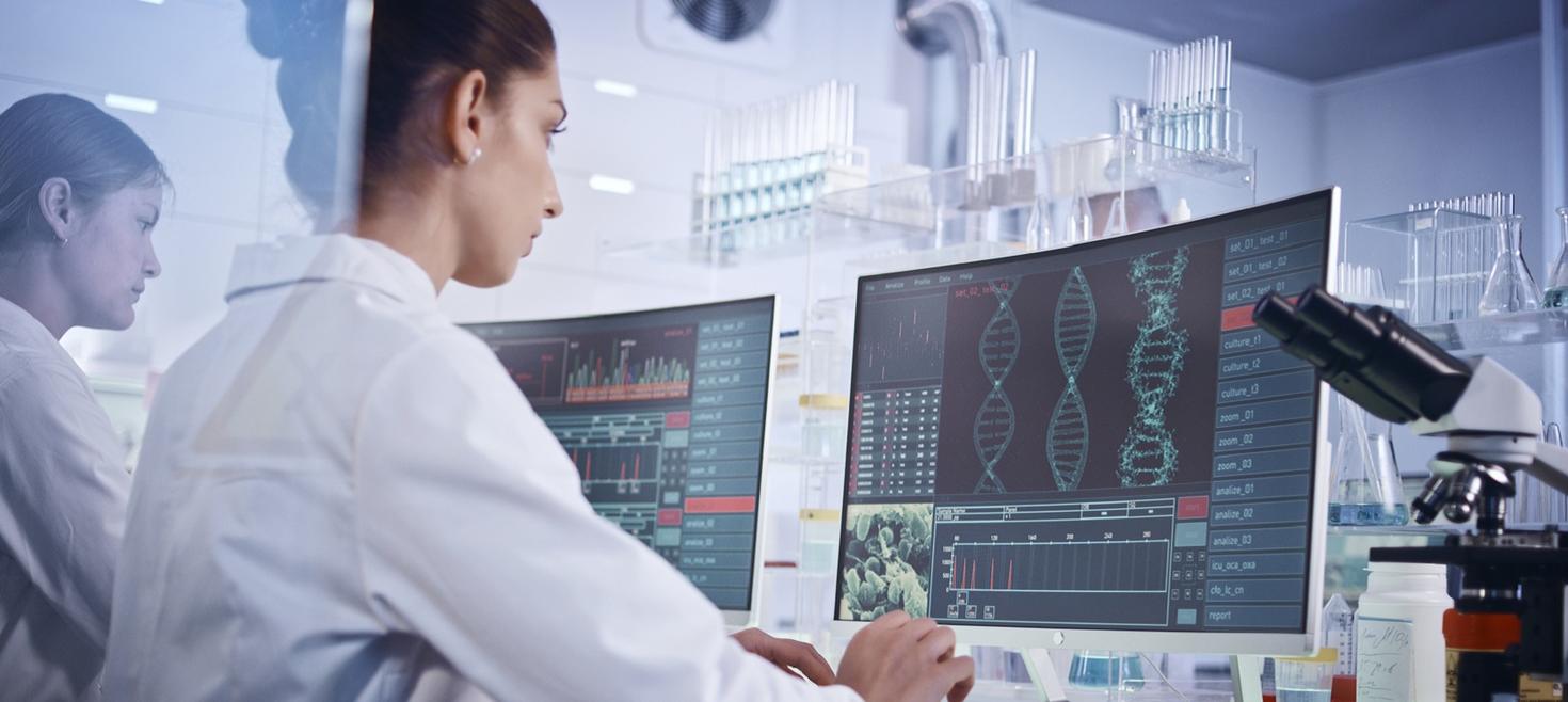 Female research team studying DNA mutations. Computer screens with DNA helix in foreground