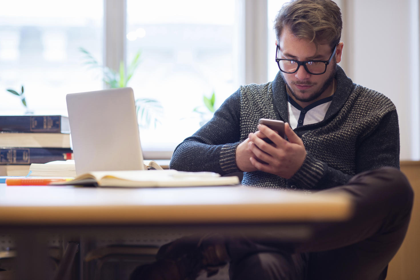 Man using smartphone at desk with computer.