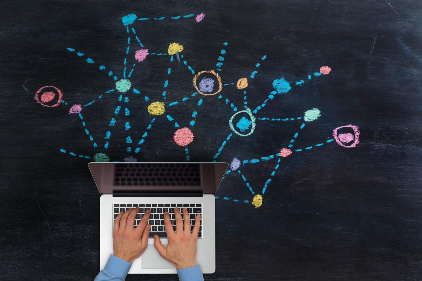 Man typing on laptop over multicoloured network