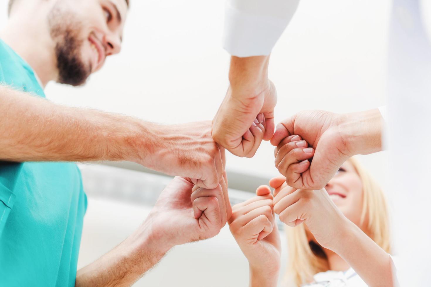 Doctor, surgeon and nurse join fists together