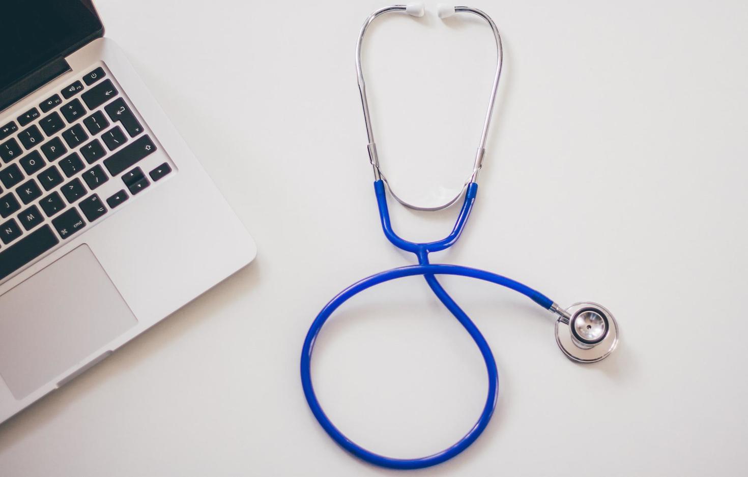 Blue stethoscope beside a MacBook